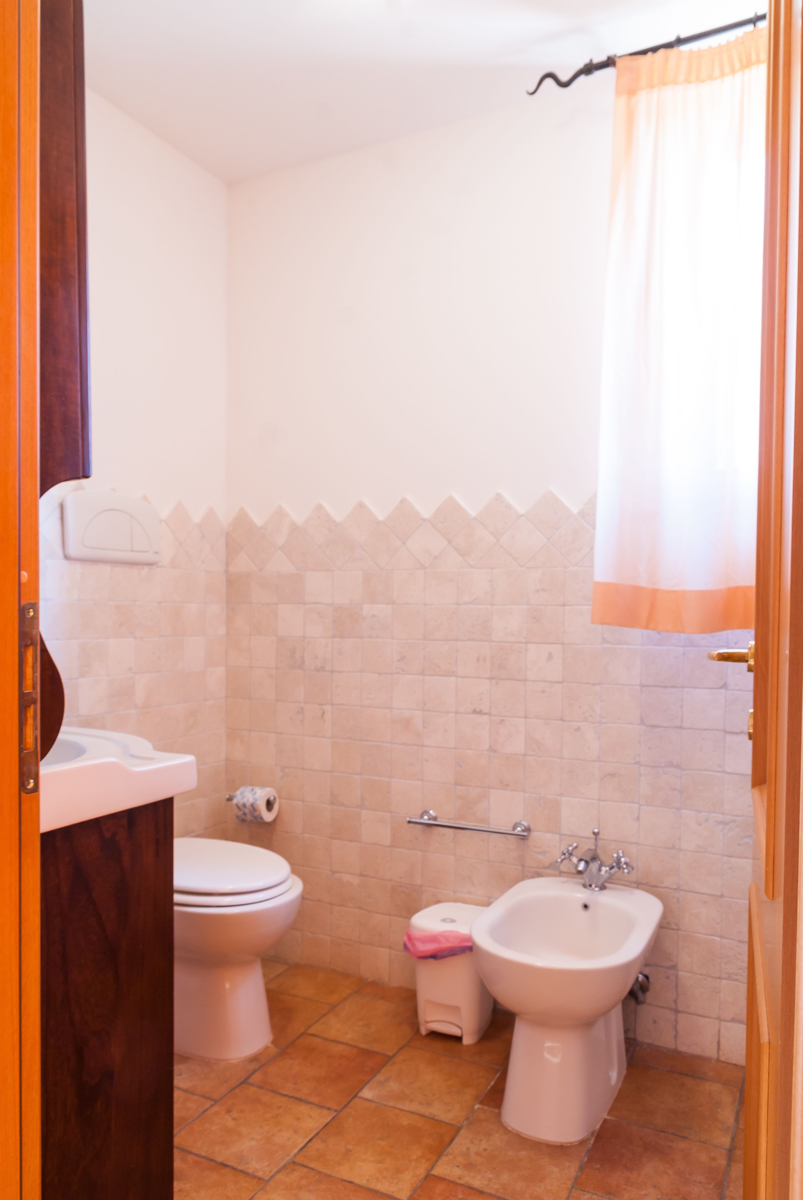 A bathroom with a toilet, bidet, and a small trash bin.