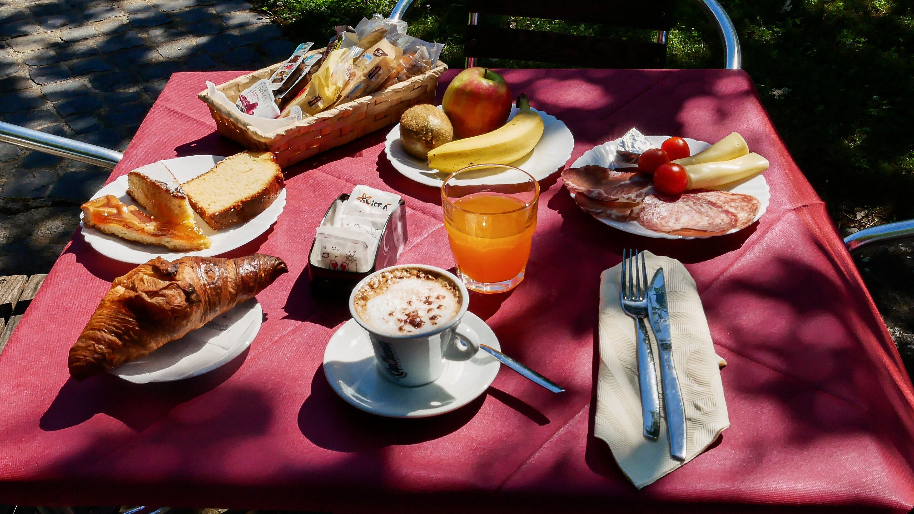 A picnic setup with various food items and a drink on a red tablecloth.