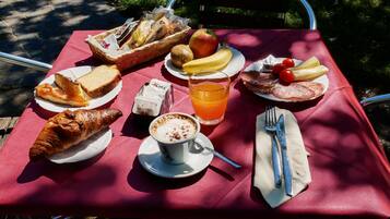 A picnic setup with various food items and a drink on a red tablecloth.