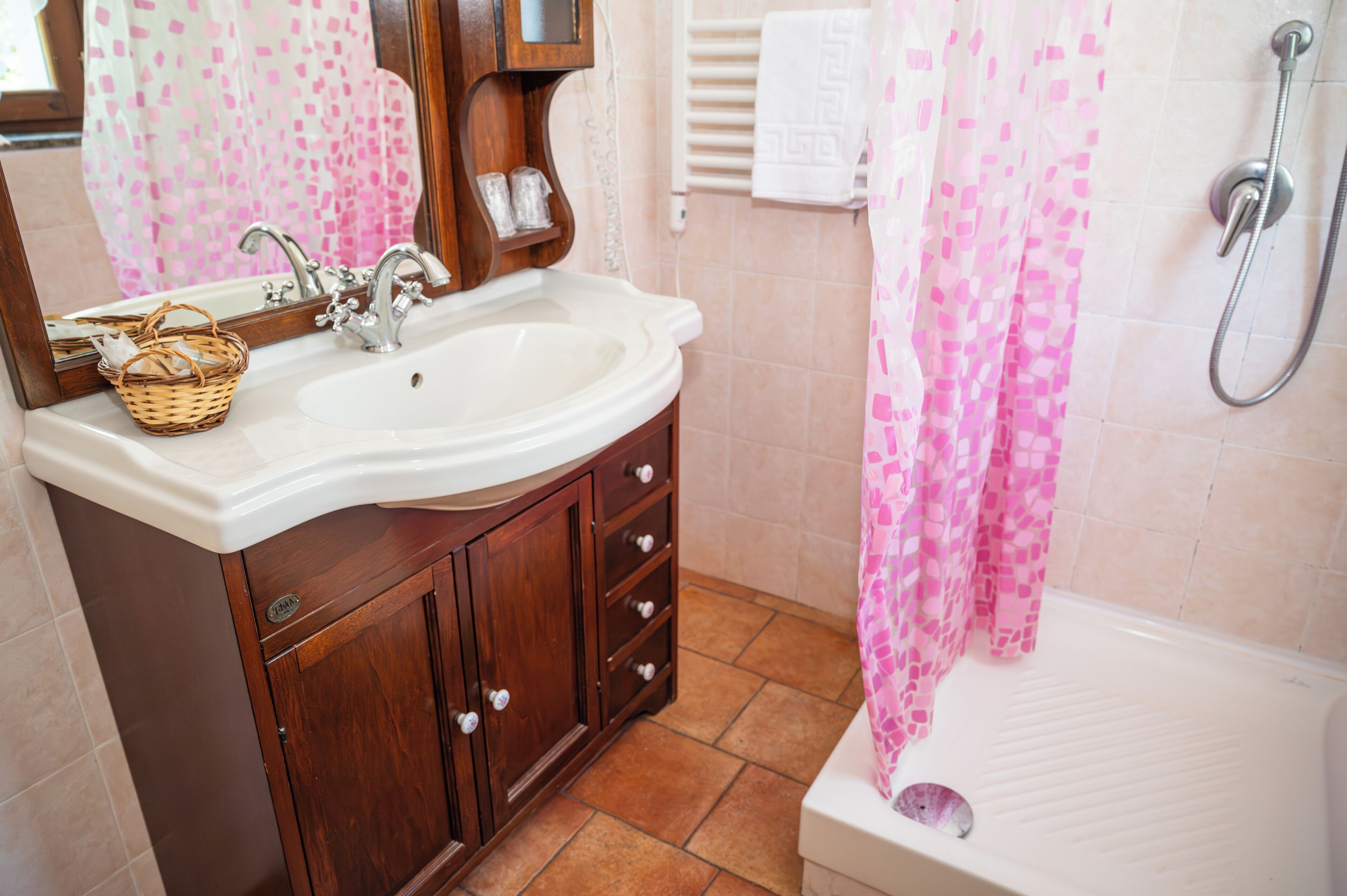 A bathroom with a sink, wooden vanity, and a shower.