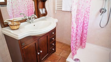 A bathroom with a sink, wooden vanity, and a shower.
