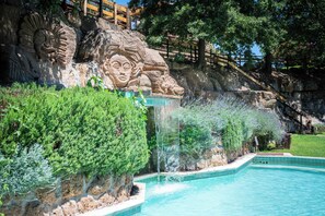Una piscina con una cascada y una escultura de piedra.