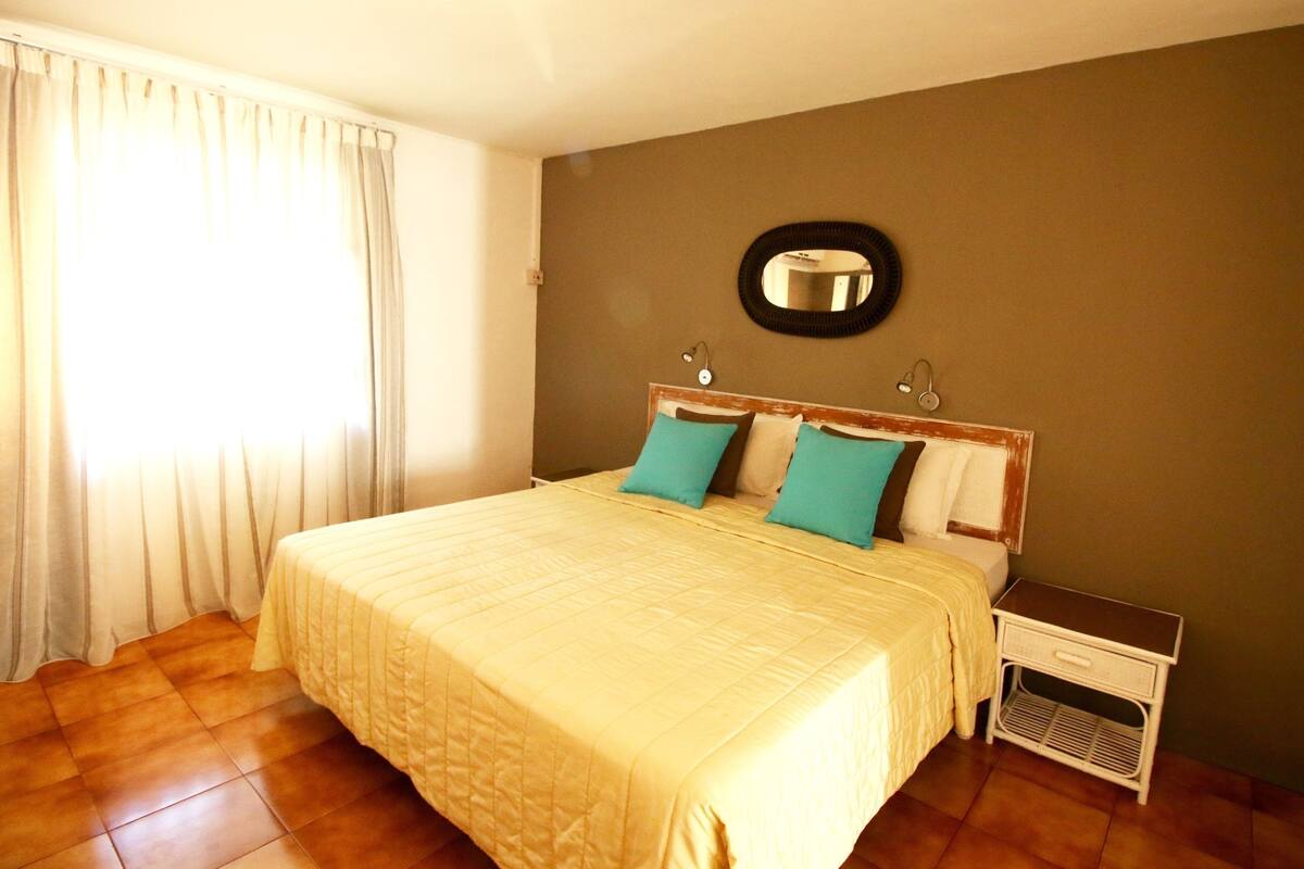 Een slaapkamer met een groot bed, een nachtkastje en een spiegel aan de muur.