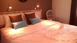 A hotel room with a bed, pillows, a chair, and a mirror on the wall. - Residence Villas Mont Choisy (Mont Choisy)
