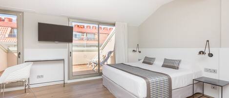 A bedroom with a bed, a TV, a desk, and a balcony.