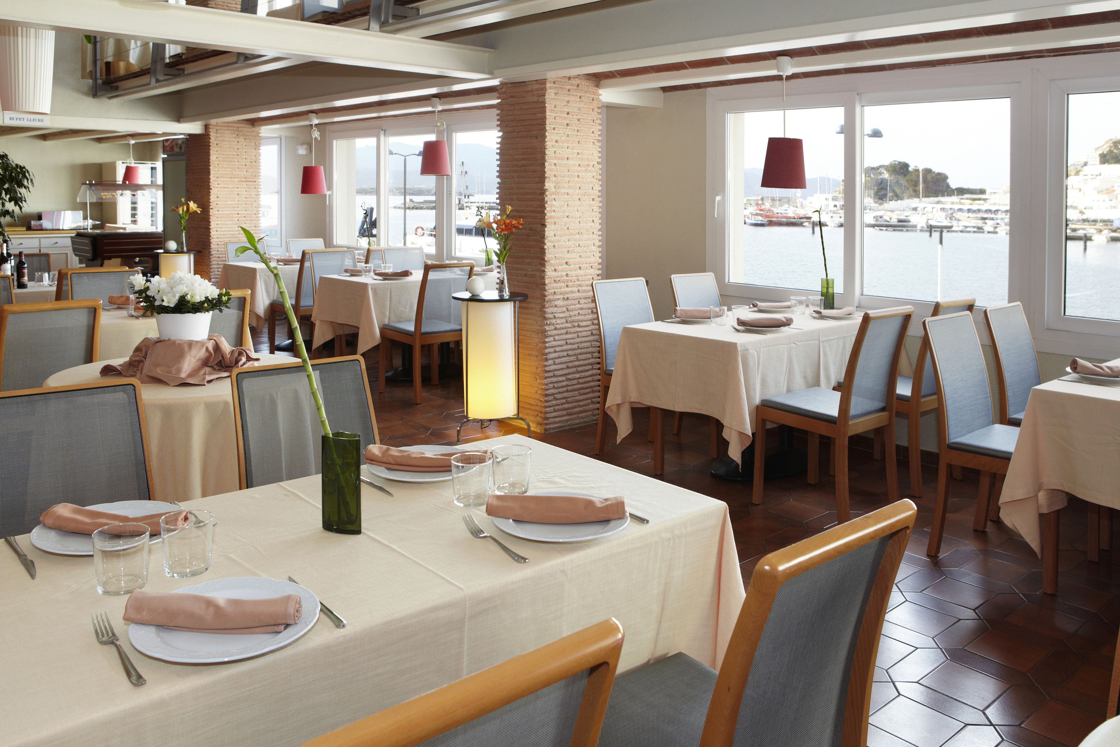 Un restaurante con mesas dispuestas para comer, sillas y vistas al agua.