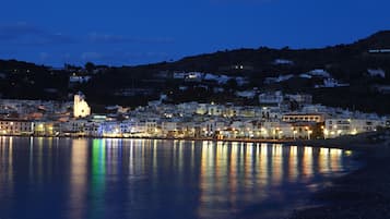 Un pueblo costero al anochecer con una iglesia destacada y edificios residenciales a lo largo del paseo marítimo.
