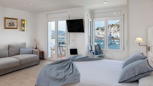 Een hotelkamer met een bed, een bank, een televisie en uitzicht op zee.