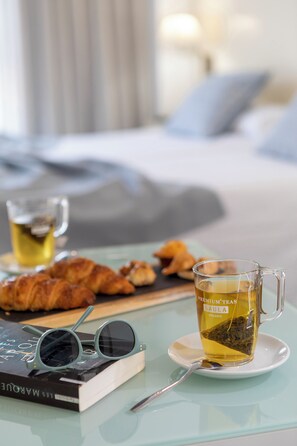 Een glazen beker thee, een boek en croissants op een tafel.
