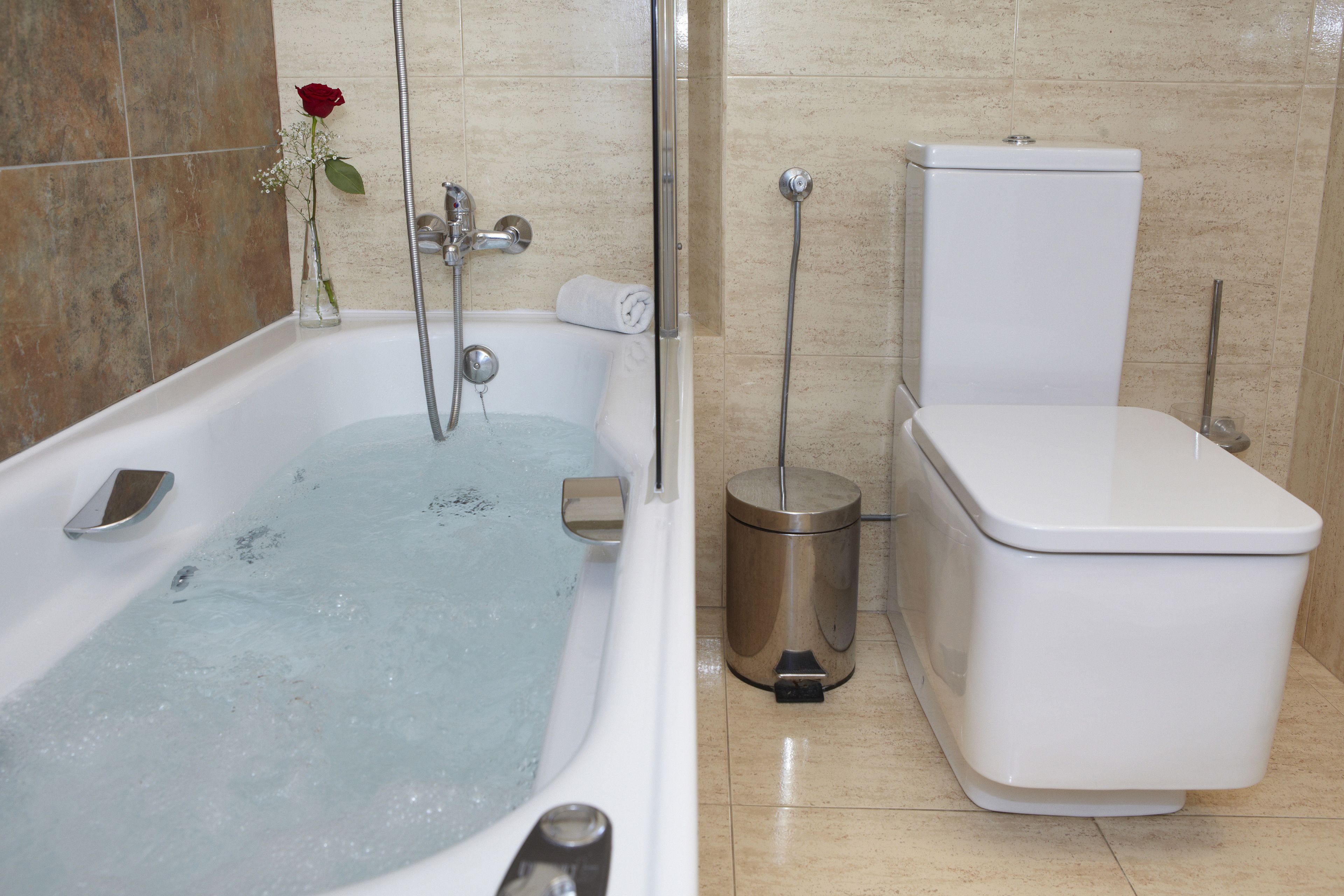 A bathroom with a bathtub, toilet, and a trash can.