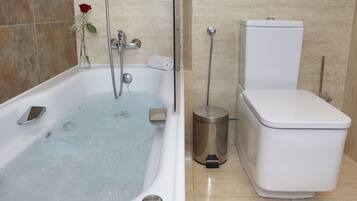 A bathroom with a bathtub, toilet, and a trash can.