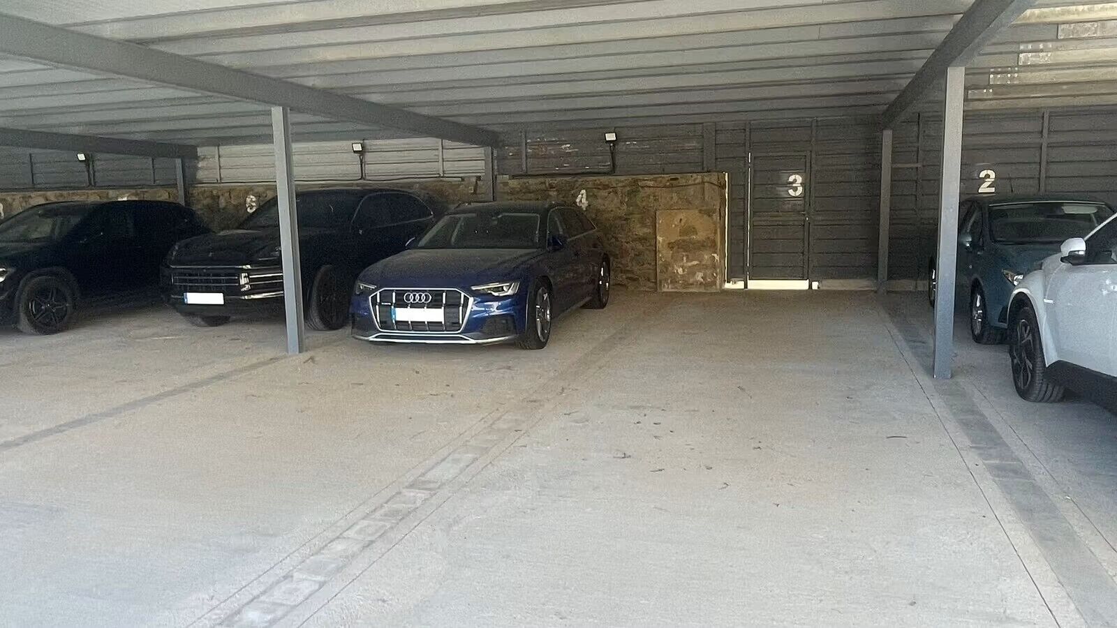 A covered parking garage with multiple cars parked in designated spaces.