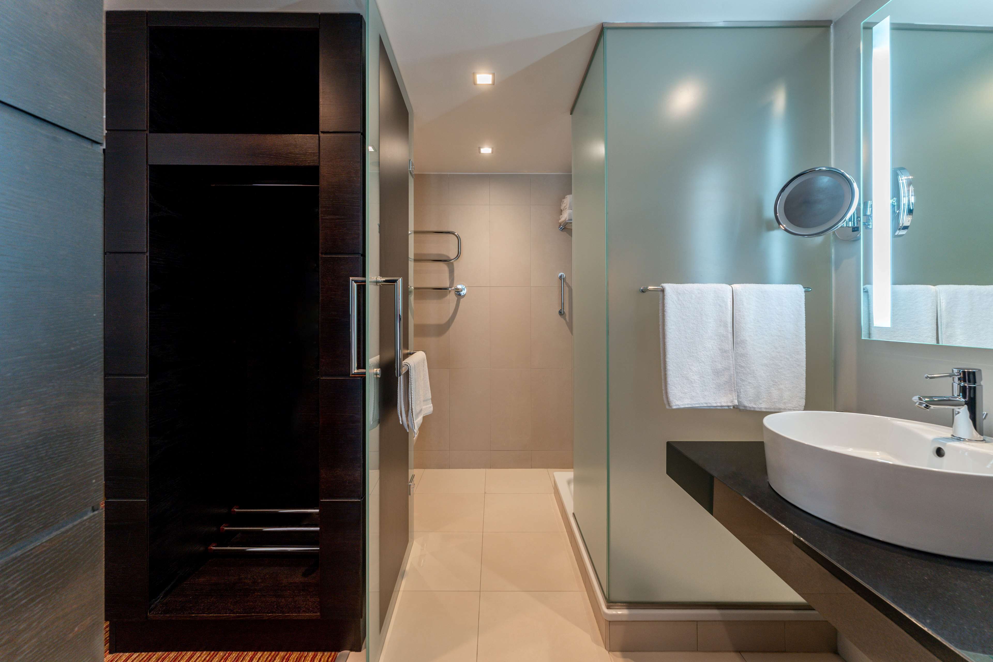Un baño moderno con ducha de vidrio, un lavabo espacioso y un espejo.