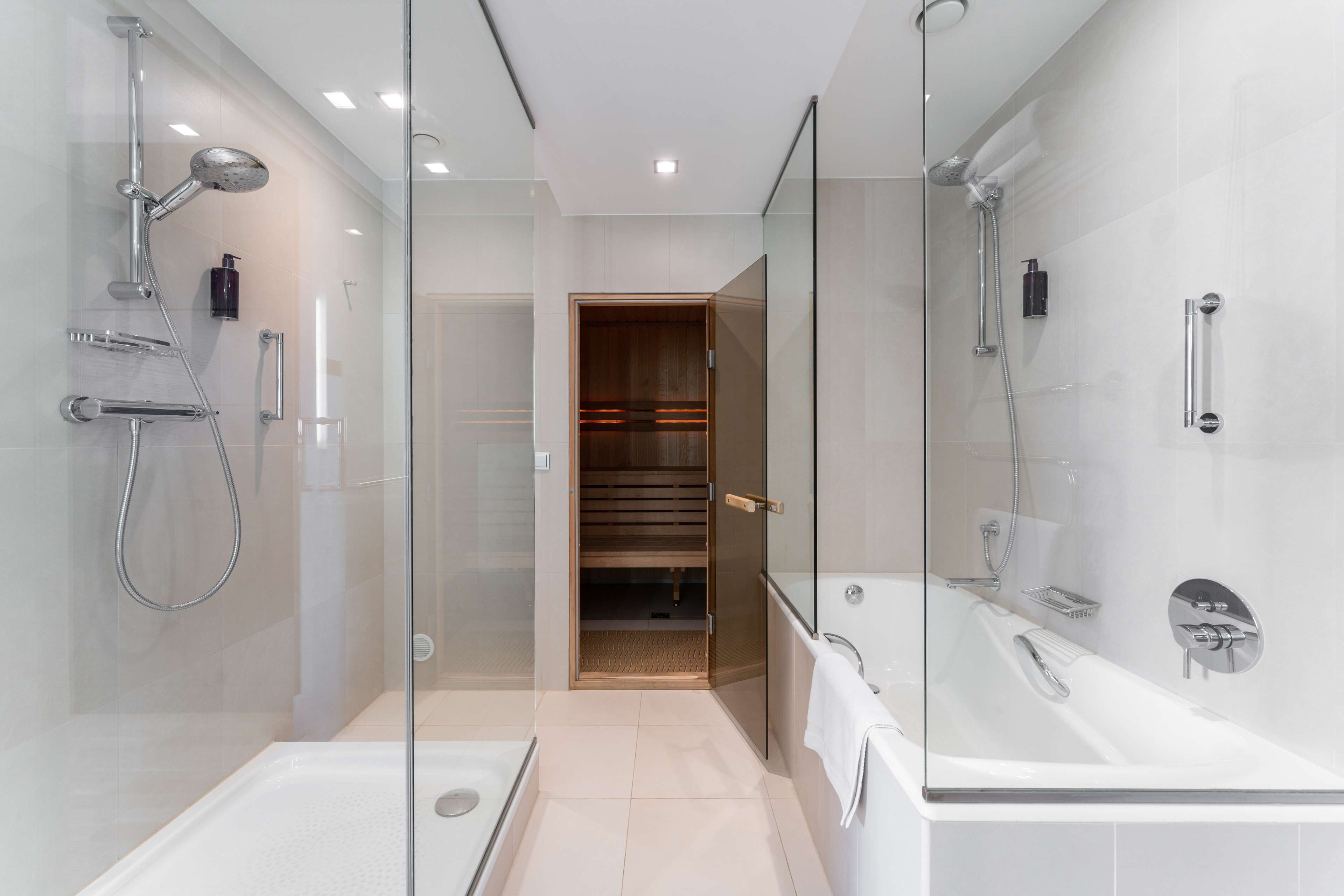 A modern bathroom with a glass-enclosed shower, a walk-in closet, and a separate bathtub.