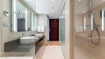 A modern bathroom with a glass-enclosed shower, a vanity with a large mirror, and a bathtub.