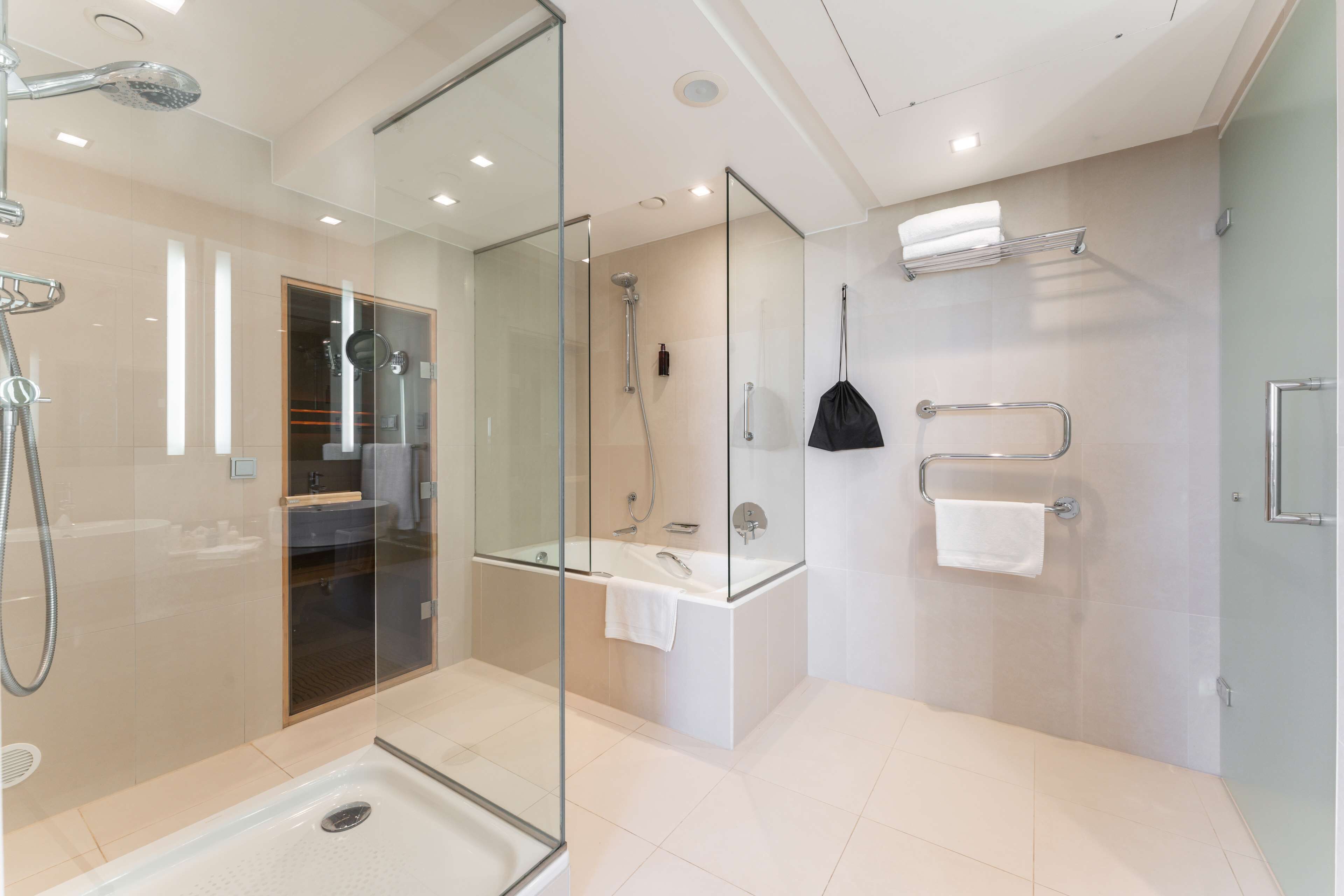 Un baño moderno con ducha envuelta en vidrio, una bañera independiente y un tocador con toallero.