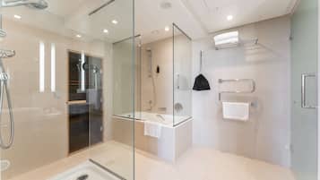 Un baño moderno con ducha envuelta en vidrio, una bañera independiente y un tocador con toallero.