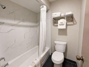 A bathroom with a bathtub, toilet, and towel rack. - Spanish Trails Inn (Mesquite)