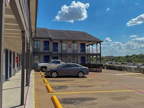 A building with a parking lot, a covered walkway, and a two-story structure with balconies. - Spanish Trails Inn (Mesquite)