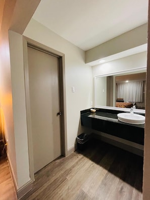 A bathroom with a white sink, a mirror, and a door. - Spanish Trails Inn (Mesquite)