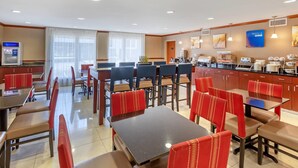 A hotel dining area with tables and chairs, a refrigerator, and a coffee station. - Comfort Inn & Suites Charleston Airport Convention Center (North Charleston)