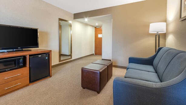 A hotel room with a flat-screen TV, a microwave, a refrigerator, a sofa, a lamp, and a mirror. - Comfort Inn & Suites Charleston Airport Convention Center (North Charleston)