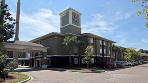 A hotel with a prominent tower, a covered entrance, and a parking lot with several cars. - Comfort Inn & Suites Charleston Airport Convention Center (North Charleston)
