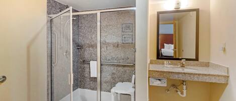 A bathroom with a glass-enclosed shower, a white toilet, and a vanity with a mirror.