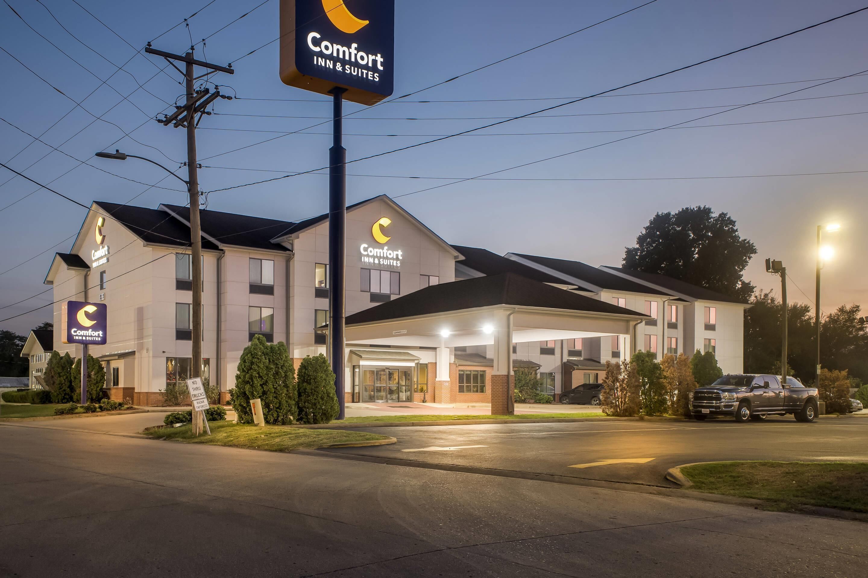 Un hotel Comfort Inn & Suites con un edificio de dos pisos, entrada cubierta y estacionamiento.