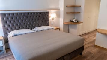 Uma cama bem arrumada com cabeceira estofada, mesa de cabeceira com abajur e estantes de madeira.
