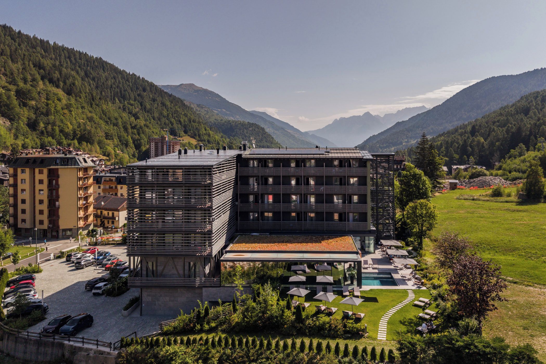 A modern hotel with a pool, surrounded by mountains.