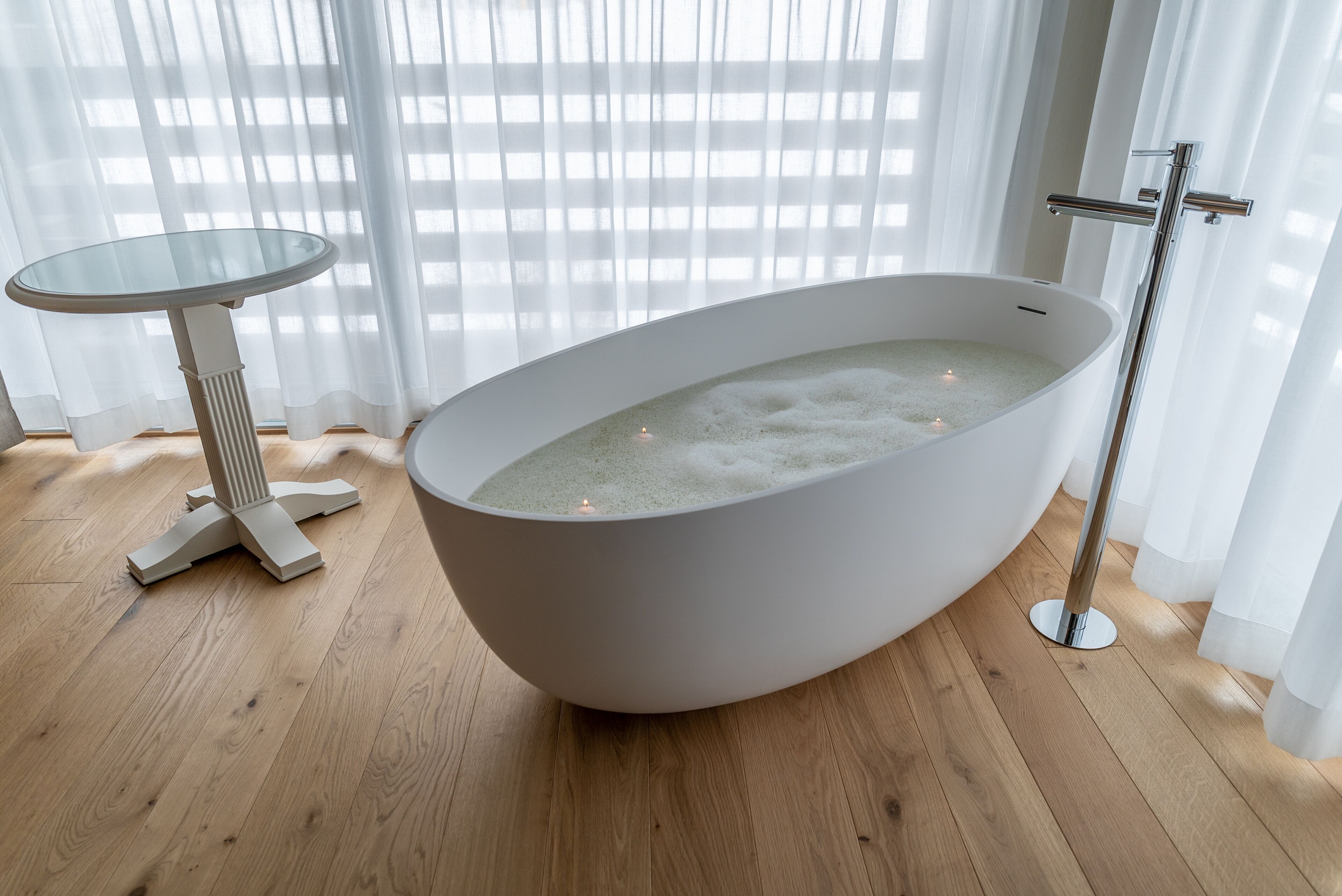 Une salle de bain moderne avec une baignoire sur pieds, une table ronde en verre et un espace douche.