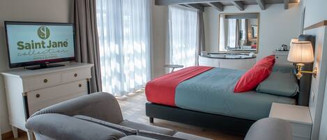 A modern hotel room with a bed, a television, a desk, and a mirror.