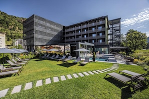 Un hotel moderno con piscina, zona de estar exterior y césped bien cuidado.