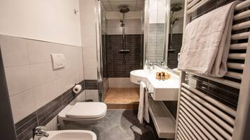 A bathroom with a toilet, bidet, sink, and shower.