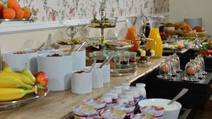 A buffet with various food items, including fruits, yogurt, and pastries.