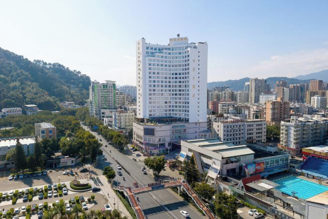A cityscape with a prominent white building, surrounded by other buildings, roads, and greenery.