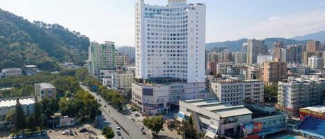 A cityscape with a prominent white building, surrounded by other buildings, roads, and greenery.