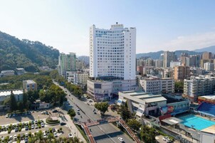 Un paisaje urbano con un edificio blanco destacado, rodeado de otros edificios, calles y áreas verdes.