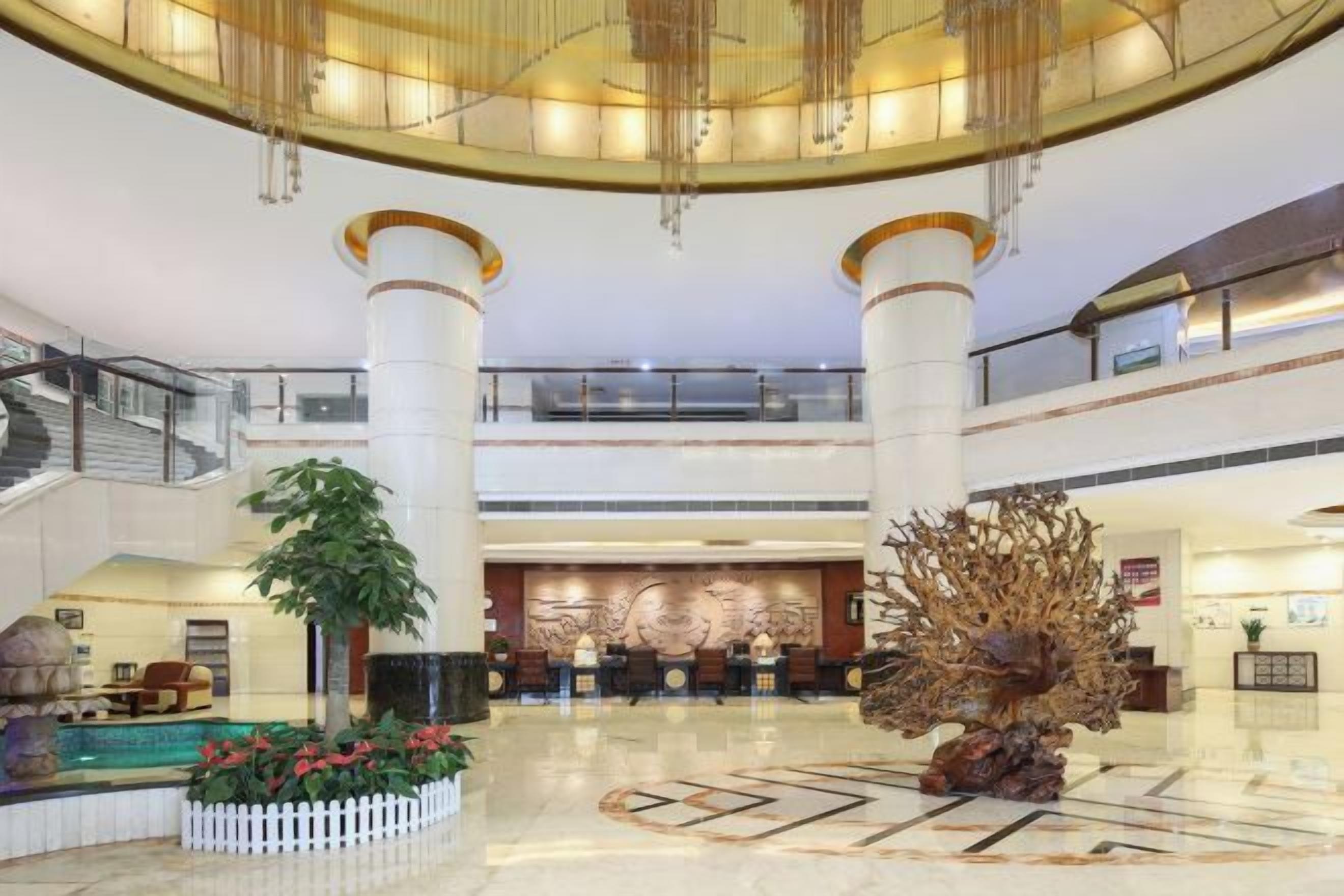 A spacious lobby with a central fountain, a reception desk, and a staircase.