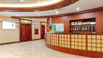 A reception area with a wooden reception desk, a bulletin board, and a tiled floor.
