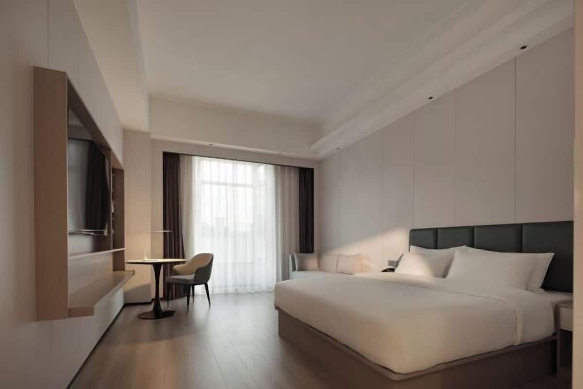 Una habitación de hotel moderna con una cama grande, un escritorio y una silla.