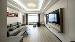 A modern living room with a sofa, TV, and a dining area.