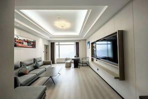 A modern living room with a sofa, TV, and a dining area.