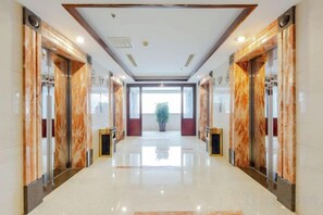 A hotel lobby with marble flooring, elevators, and a central plant. - Centron International Hotel (Longyan)