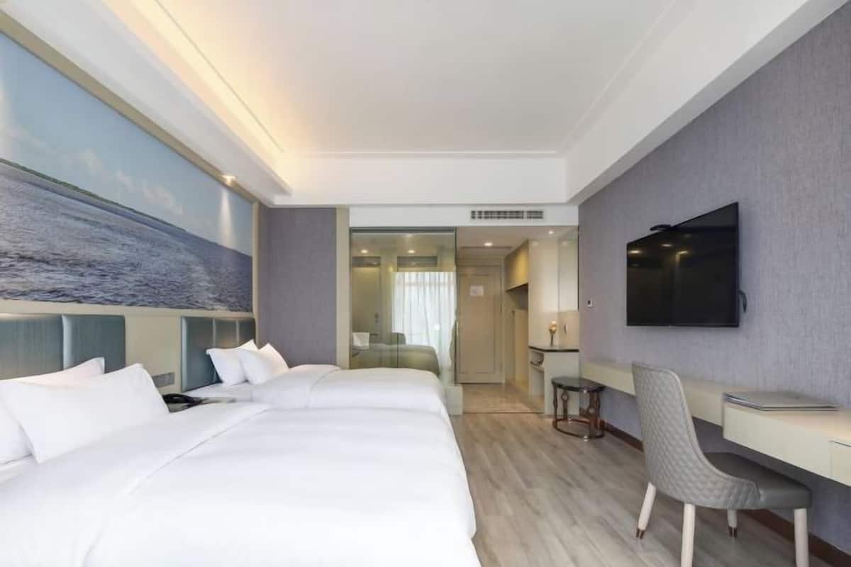 Habitación de hotel con una cama grande, un escritorio, una silla, un televisor y vistas al mar.