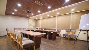 A conference room with a long table and chairs, a whiteboard, and a ceiling fan. - Hotel Classic Karol Bagh (New Delhi)