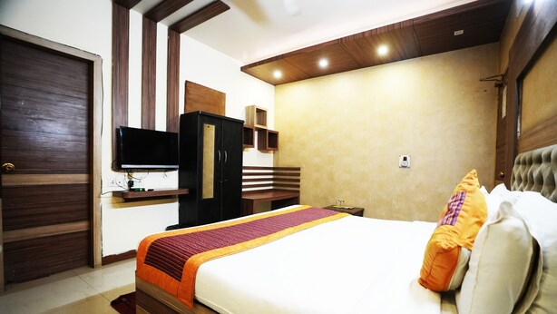A hotel room with a bed, a television, a wardrobe, and a bedside table. - Hotel Classic Karol Bagh (New Delhi)