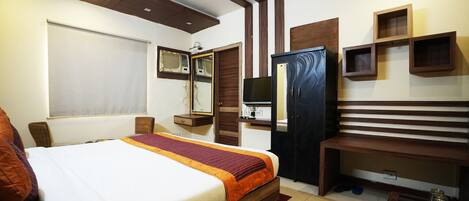 A hotel room with a large bed, a desk, a TV, and a wardrobe.