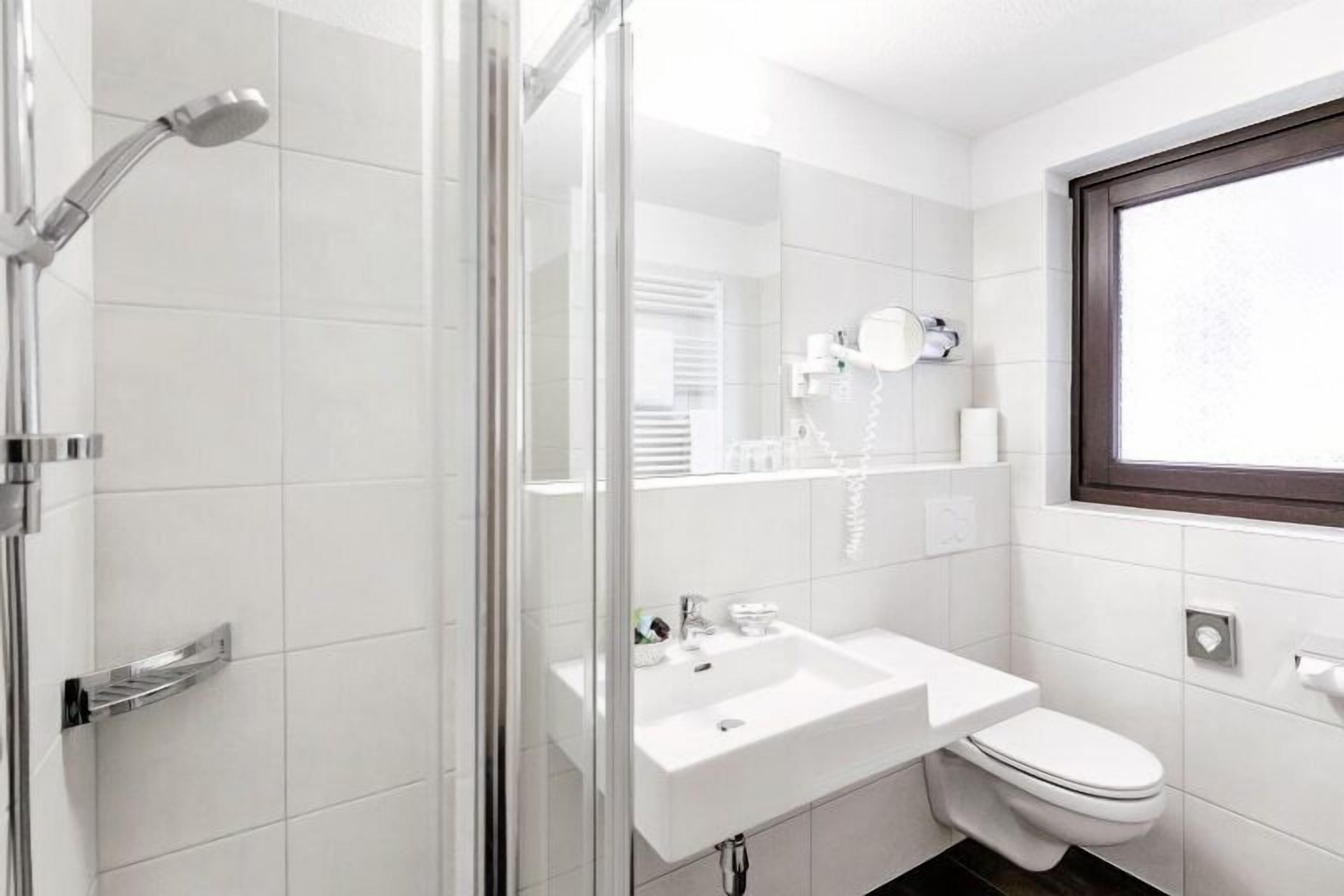 A modern bathroom with a glass shower enclosure, a white sink, and a toilet.